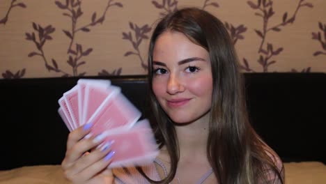 Girl-messing-around-while-playing-cards,-gives-a-wink