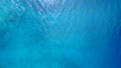 Wunderschöne-Blaue-Azurblaue-Meeresstruktur-Mit-Lebendiger-Wasseroberfläche,-Die-Das-Sonnenlicht-An-Der-Küste-Der-Bahamas-Reflektiert,-Kopierraum