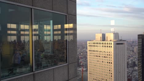 Menschen-Im-Büro-Blicken-Durch-Die-Glaswand-Eines-Hochhauses-In-Tokio,-Japan,-Auf-Die-Metropole-–-Mittlere-Aufnahme