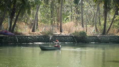 Weitwinkelaufnahme-Eines-Indianischen-Mannes,-Der-Bei-Sonnenlicht-In-Einem-Hölzernen-Kanuboot-Auf-Dem-Fluss-Schwimmt