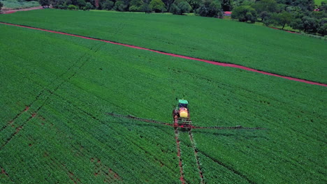 Aerial-image-of-tractor-spraying-soil-and-young-crop-in-springtime-in-field