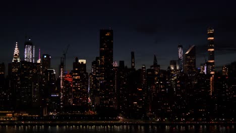 Establishing-shot-of-East-Side-Manhattan,-New-York-City-at-dusk,-with-the-traffic-on-FDR-Drive-at-the-shore-of-East-River,-Chrysler-building-and-other-skyscrapers,-filmed-from-Long-Island-City
