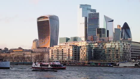 Citycruises-tour-boat-on-River-Thames-in-front-of-iconic-landmark-office-buildings-skyline