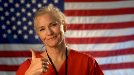 Female-nurse-walking-from-out-of-focus-US-flag-to-a-medium-tight-portrait-looking-very-relieved-and-happy