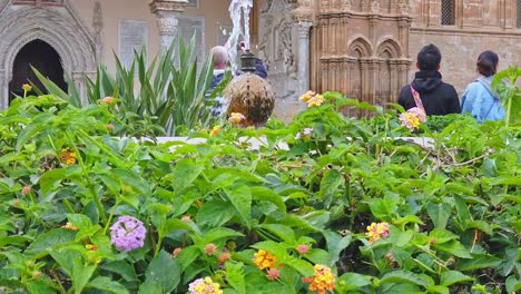 Tourists,-flowers-and-a-fountain-in-the-square-in-front-of-the-arab-norman-cathedral-of-Palermo