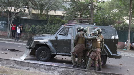 Squad-of-riot-police-use-an-armored-truck-to-hide-from-thrown-projectiles