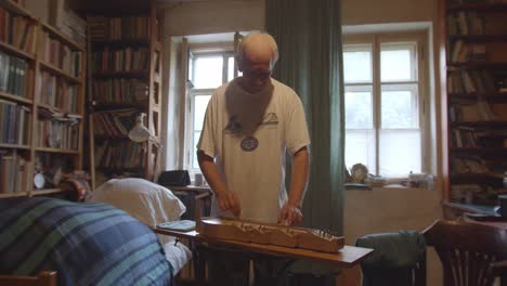 Male-musician-standing-in-living-room-paying-Zither-instrument