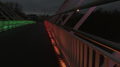Slow-pan-left-across-Steve-Prescott-colourful-illuminated-bridge-crossing-in-town-urban-scene-at-night