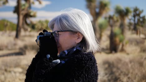 Eine-Erwachsene-Fotografin,-Die-Mit-Ihrer-Altmodischen-Filmkamera-Und-Ihrem-Objektiv-In-Einer-Wüstenlandschaft-Aus-Nächster-Nähe-Fotografiert