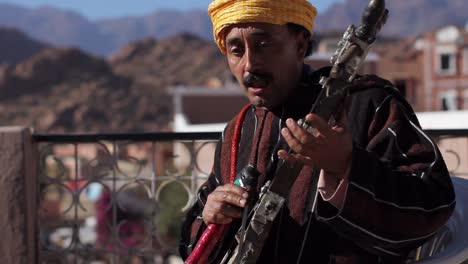 Hintergrundbeleuchtete-Nahaufnahme-Eines-Berbermusikers,-Der-In-Tafraoute,-Marokko,-Das-Streichinstrument-Rabab-Spielt-Und-Traditionelle-Lieder-Singt