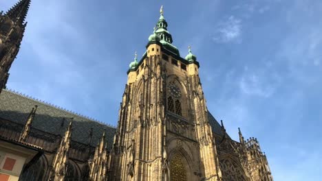 Clock-tower-of-St-Vitus-Cathedral-in-Prague-rises-into-blue-sky,-low-angle