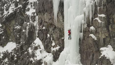 Amazing-aerial-lone-climber-scaling-ice-cascade-Maineline,-Mount-Kineo-4K