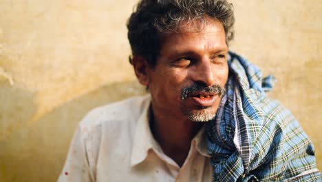 Indian-man-chewing-with-the-sun-on-his-face,-looking-into-the-camera
