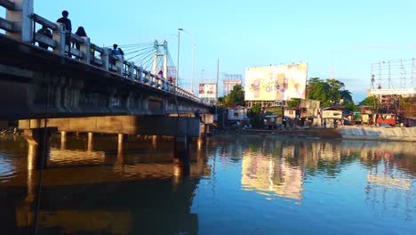 Bankerohan-Bridge-Davao-city-Philippines-with-man-fishing-and-people-walking-on-the-bridge-as-well-as-houses-and-water