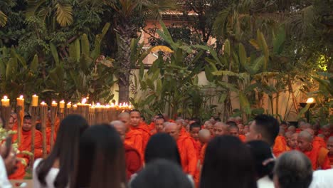 Medium-Exterior-Handheld-Shot-of-Monks-Sitting-Down-For-Ceremony-in-Evening-Time