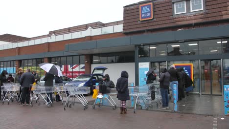 People-are-queueing-outside-of-the-supermarket-chain-Aldi-before-it-is-open-in-the-morning-to-shop-and-stock-up-on-food-during-the-Corona-virus-crisis-and-in-preparation-for-quarantine-in-the-UK