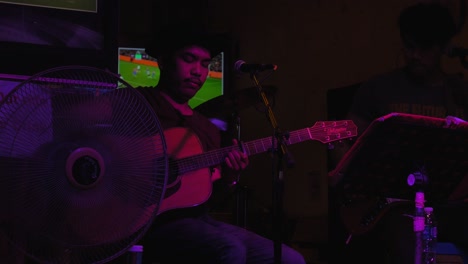 Hombre-Tailandés-Con-Sombrero-Tocando-La-Guitarra-En-Khaosan-Road-En-Bangkok,-Tailandia
