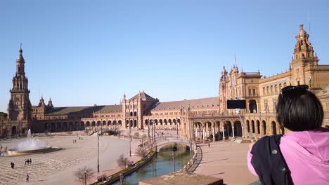 Woman-takes-picture-of-Plaza-de-Espana-from-balcony-in-Seville-with-selfie-stick