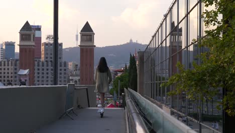 Junge-Frau-Läuft-Auf-Einem-Elektroroller-über-Die-Brücke-Am-Espanya-Platz-In-Der-Stadt-Barcelona