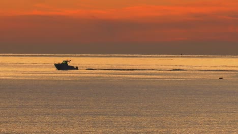Motor-boat-leaving-harbor-under-dawn-sky,-silhouette