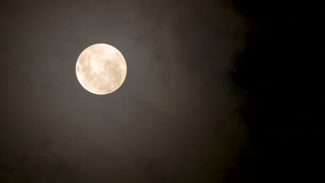 Full-glowing-moon-with-clouds-being-blown-by-winds-during-storm-at-nights