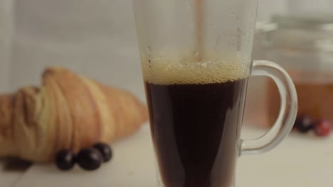 Pouring-fresh-coffee-at-breakfast-with-honey-and-croissants