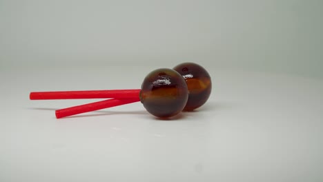 Two-Brown-Colored-Lollipop-On-A-Crossed-Red-Stick---Close-Up-Shot