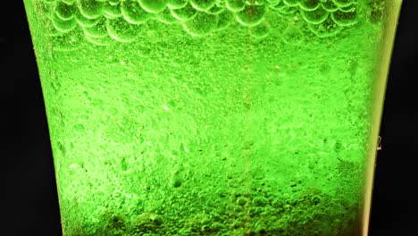 Makroaufnahme-Eines-Glases-Mit-Vielen-Grünen-Blasen,-Die-Im-Wasser-Schwimmen-Und-Tropfen