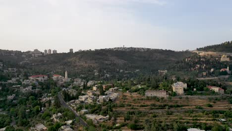 Aerial-fly-over-Arabic-village-in-the-Jerusalem-area,-Buildings-on-hill-side-with-green-forest-vegetation