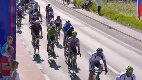 Big-group-of-bicycle-race-competitors-passing-by-people-watching-and-waving-at-them