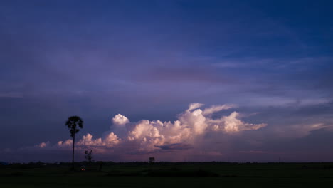 Bubbling-Storm-Clouds-with-silhouetted-palm-tree-at-Sunset-over-the-Tonle-Sap-Lake,-Cambodia