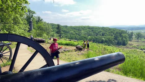 Young-boy-carrying-rifle-passes-by-Civil-War-Cannon-on-Little-Round-Top