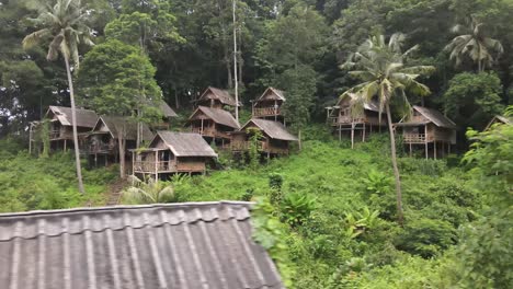 Empty-bungalows-in-a-jungle-on-a-green-mountain,-aerial-drone-shot