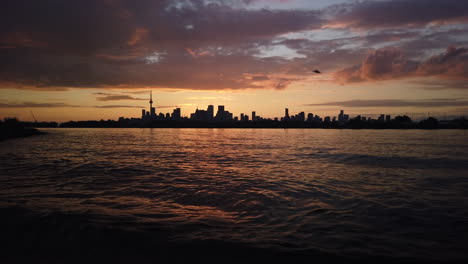 Wide-shot-of-Toronto-skyline-and-Lake-Ontario-silhouetted-against-a-twilight-sky-and-multi-coloured-clouds