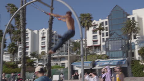 A-man-swinging-on-the-traveling-rings-at-Santa-Monica-Beach-in-Los-Angeles-California