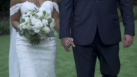 Bride-and-groom-walking-hand-in-hand-holding-bouquet