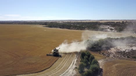 Combine-gathering-corn-and-kicking-up-dust-in-the-dry-farm-field---aerial-view