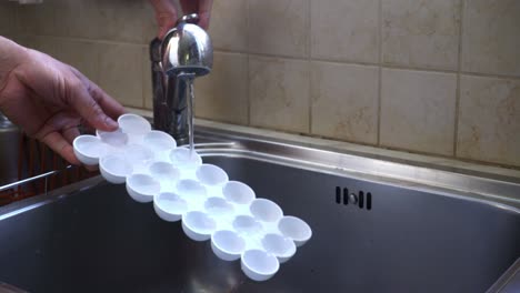 Caucasian-man-filling-an-ice-cubes-tray-with-water-at-home