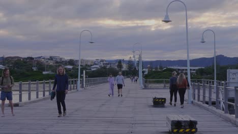 Gente-Caminando-En-El-Embarcadero-De-Madera---Viaje-Al-Atardecer-En-Coffs-Harbour,-Nsw,-Australia---Posibilidad-Remota