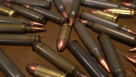 Slider-close-up-of-AR-15-and-9mm-gun-ammo-laying-on-a-glass-table