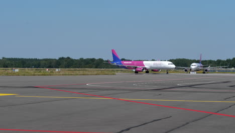An-Airplane-Of-Wizzair-Airline-Running-Slowly-On-The-Airfield-Of-Eindhoven-Airport,-Eindhoven,-Netherlands-Ready-For-Takeoff---wide-shot