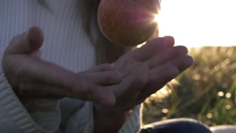 Frau-Wirft-Saftigen-Roten-Apfel-Vor-Sonnendurchflutetem-Hintergrund