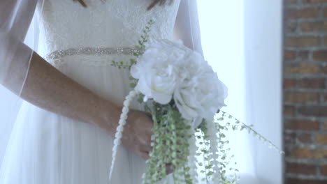 Bride-holding-bouquet-wearing-white-dress-prepared-for-wedding-day-ahead