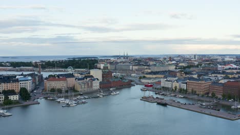 Slow-aerial-pan-of-boats-along-the-waterfront-with-a-ferris-wheel-in-view-at-dusk,-Finland