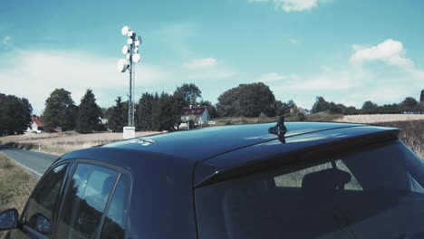 Black-car-with-network-communication-mast-for-automatic-driving-and-steering-of-the-car-in-the-background