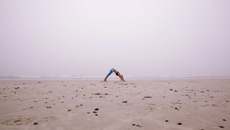 Side-view-of-a-young-woman-doing-a-sun-salutation-on-the-beach