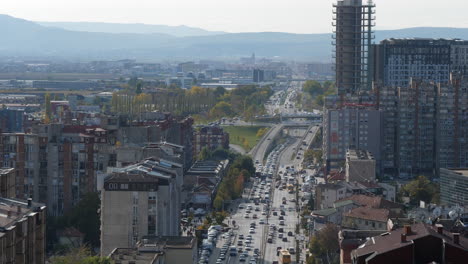 Static-Aerial-View-of-Downtown-Avenue-Traffic-in-Pristina,-Kosovo-on-Sunny-Fall-Day