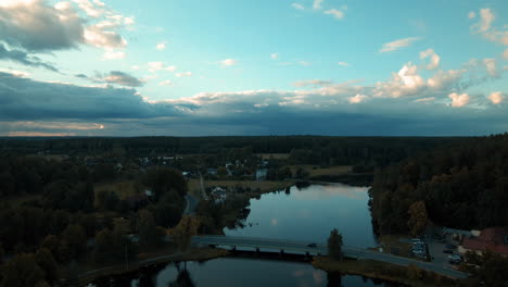 Aerial-view-of-nature-lake-with-bridge-after-sunset-and-cloudscape-in-background