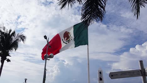 The-Mexican-flying-from-a-staff-flaps-gently-in-the-breeze-at-the-horbor-of-Cozumel-Island-in-Mexico