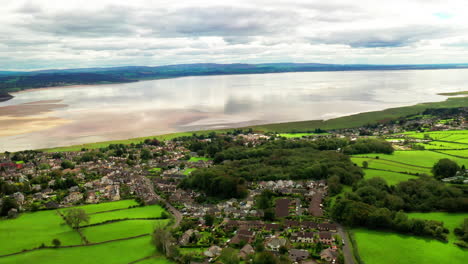 Aerial-view-of-a-tidal-bay-with-a-countryside-town-in-the-foreground,-bright-sunny-daylight